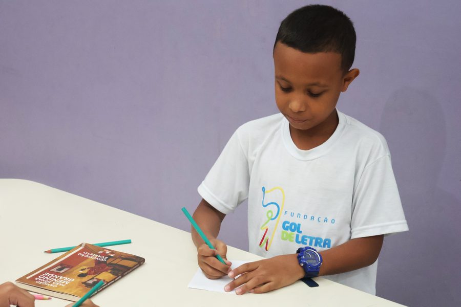 Criança em atividade de letramento com o livro Gol de Letrinhas